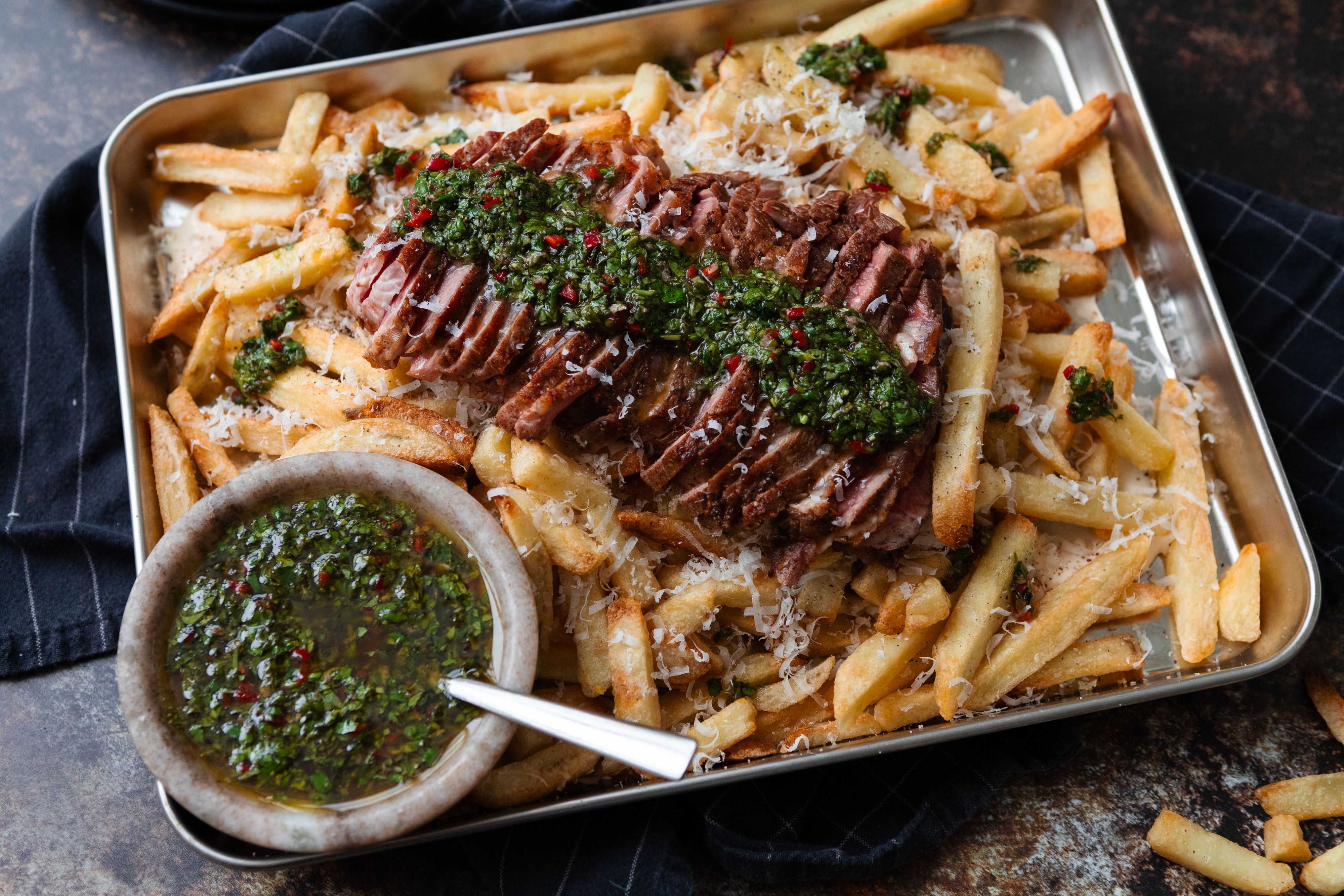 Loaded fries med biffkjøtt og chimichurri på stekebrett.