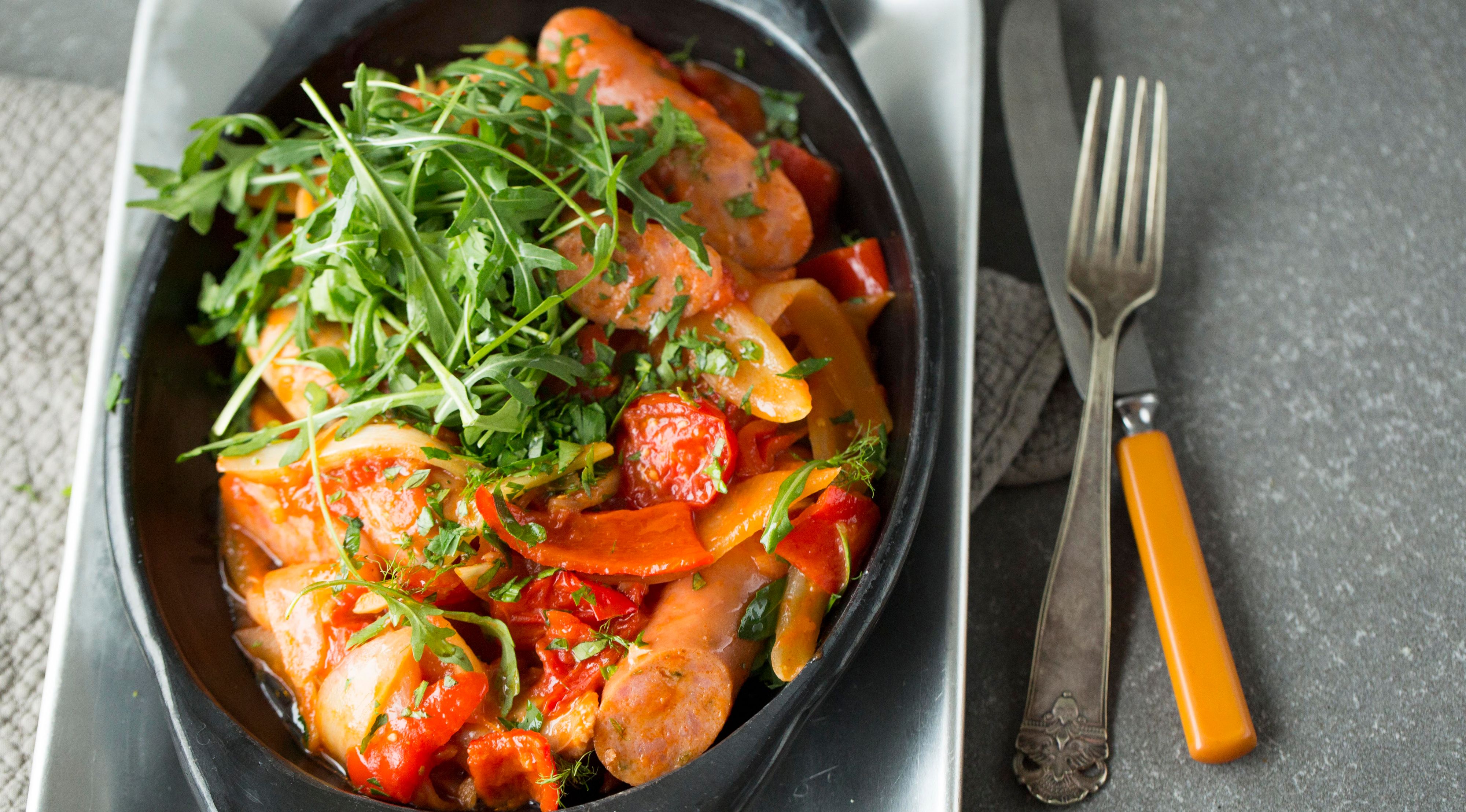 Pølsegryte i svartskål på hvit tallerken