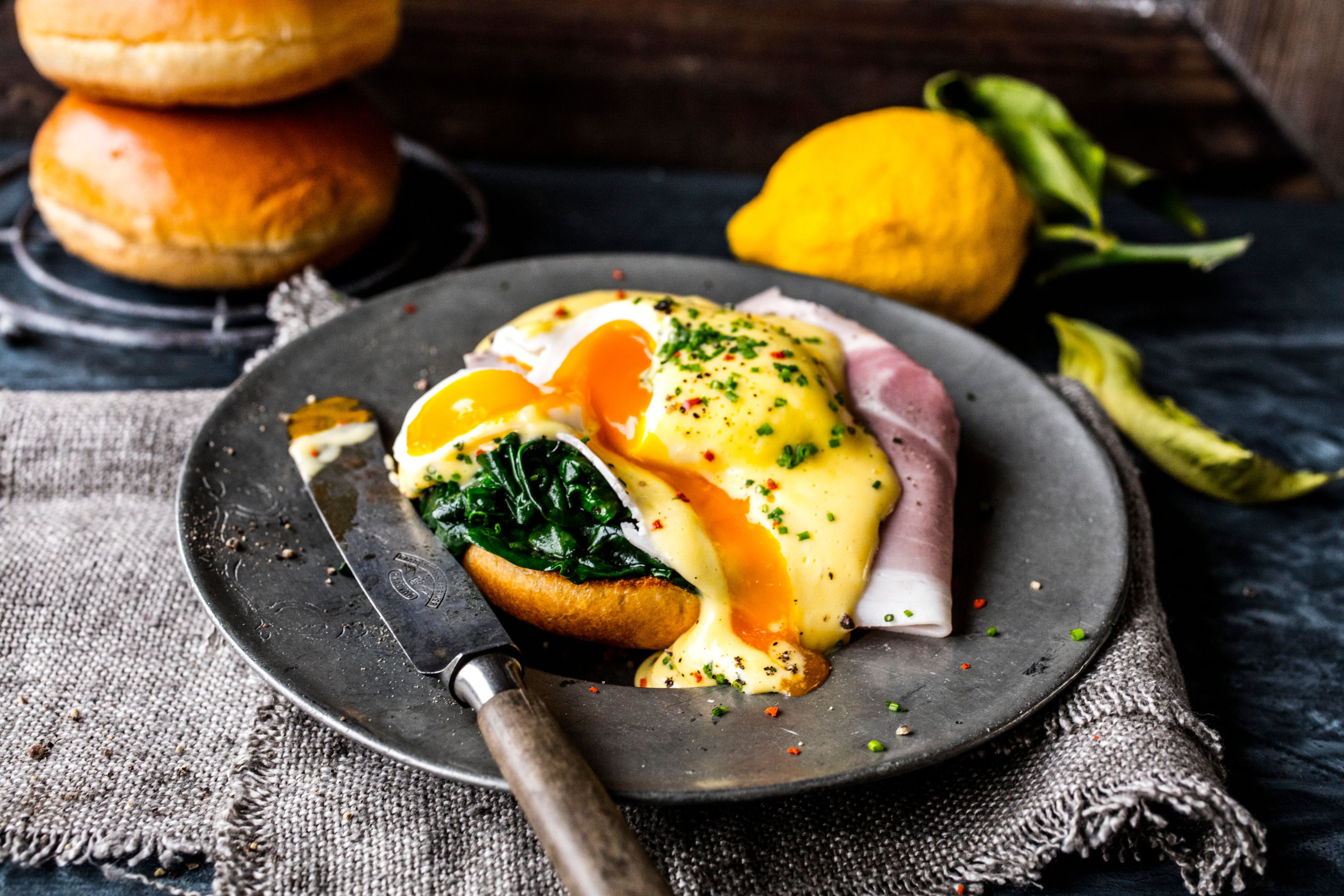 Eggs Benedict med spinat og skinke på mørkegrå tallerken