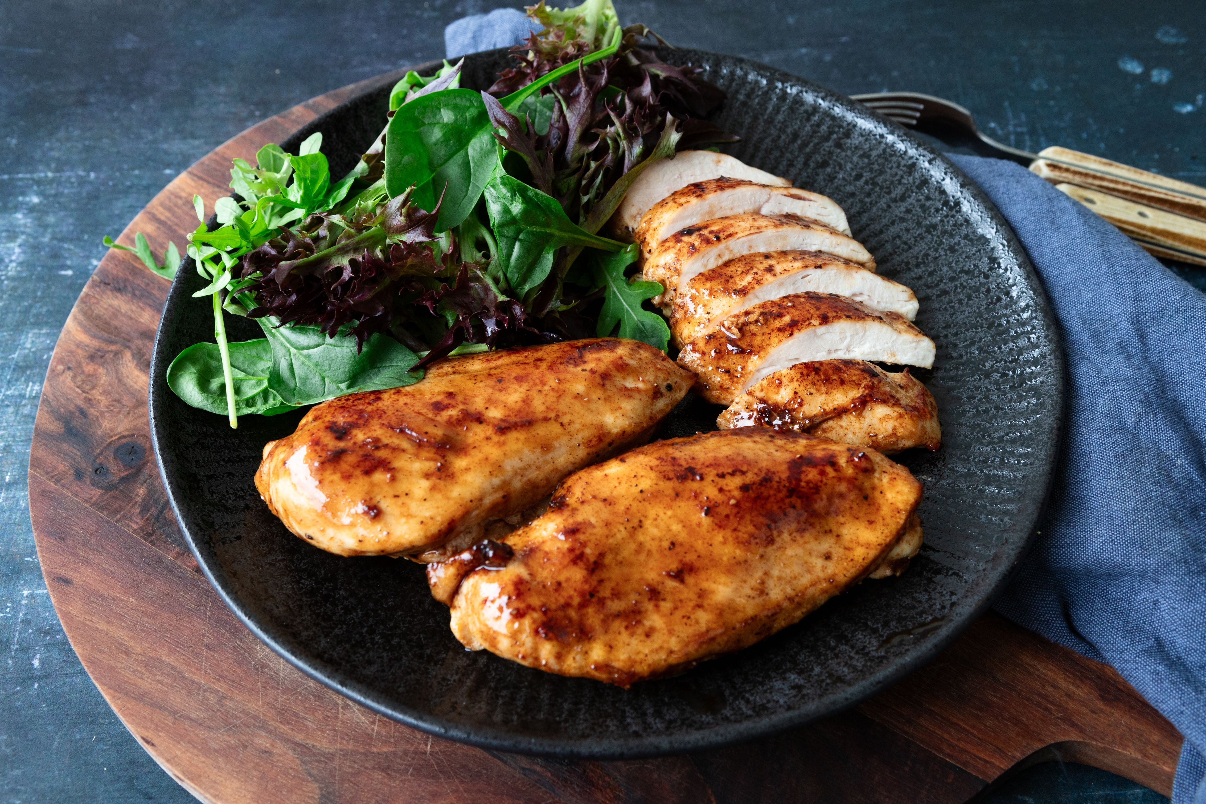 Kyllingfilet stekt i airfryer, servert på svart tallerken med grønn salat